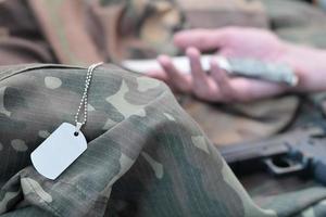 el símbolo vacío del ejército de un soldado militar muerto yace sobre ropa de camuflaje. suicidio durante el servicio militar en el ejército ruso foto