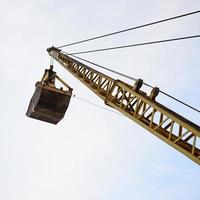 Old yellow mechanical clamshell grab on blue sky background photo