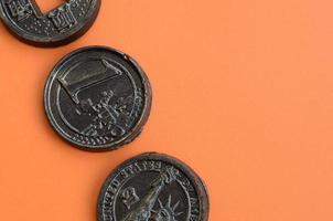 tres productos de chocolate en forma de monedas de euro, estados unidos y japón yacen sobre un fondo de plástico naranja. un modelo de monedas en efectivo en forma comestible foto