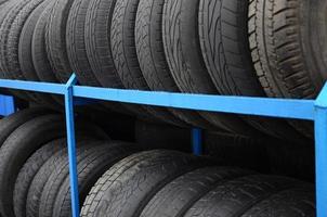 Rack with variety of car tires in automobile store. Many black tires. Tire stack background. Selective focus photo