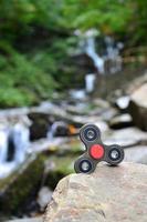 The wooden spinner lies on the rocks against the background of a small waterfall and a river photo