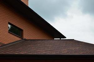 The house is equipped with high-quality roofing of shingles bitumen tiles. A good example of perfect roofing. The roof is reliably protected from adverse weather conditions photo