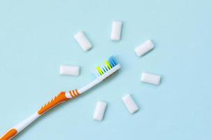 Toothbrush and chewing gums lie on a pastel blue background. Top view, flat lay. Minimal concept photo