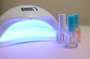 luces de lámpara de diodo uv para uñas y juego de esmalte de uñas cosmético para manicura y pedicura sobre fondo pastel foto