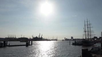 visie van de silhouet van Hamburg haven tegen de laag zon met licht reflecties Aan de water.