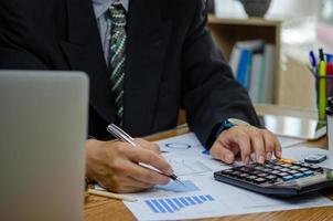 hombre de negocios que trabaja en la oficina con un documento en su escritorio. planificación del informe del gráfico de papeleo que analiza el concepto de análisis financiero y de inversión. foto