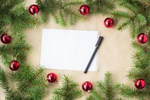 Fir tree branches decorated with red christmas balls as border on a rustic holiday background frame with copy space pen photo