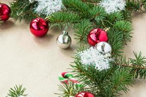 Festive christmas border with red and silver balls on fir branches and snowflakes on rustic beige background photo