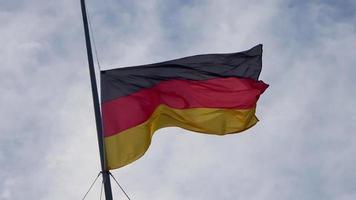 Duitse vlag bij een vlaggenmast die langzaam in de wind tegen de lucht beweegt video