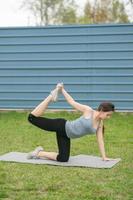 Fitness. Girl sitting on the lawn in the yard of her house, doing excise. photo