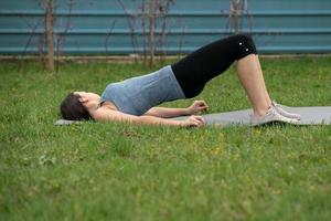 Fitness. Girl sitting on the lawn in the yard of her house, doing excise. photo