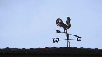 The old wind vane with a rooster symbol icon on the roof, traditional technology equipment for forecast and measuring windy weather in the air, vintage decoration, aiming wind direction instrument. photo