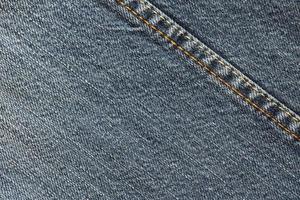 Detailed abstract texture of dark blue denim cloth. Background image of old used denim trousers fabric photo