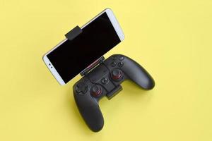 Modern black gamepad for smartphone on yellow background. Mobile video gaming device photo