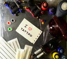 I love tattoo. The text is written on a small sheet of paper among various equipment for tattooing photo