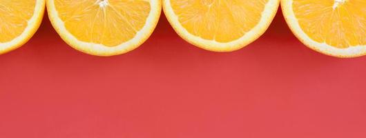 Top view of a several orange fruit slices on bright background in red color. A saturated citrus texture image photo