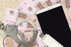 100 russian rubles bills and smartphone with police handcuffs. Concept of hackers phishing attacks, illegal scam or malware soft distribution photo