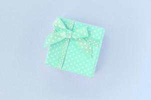Small blue gift box with ribbon lies on a violet background photo