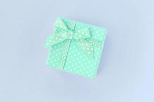 Small blue gift box with ribbon lies on a violet background photo