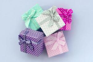 montón de pequeñas cajas de regalo de colores con cintas se encuentra sobre un fondo violeta foto