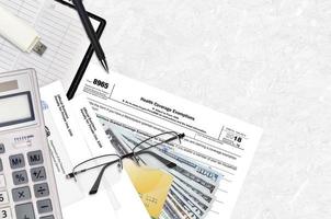 IRS form 8965 Health Coverage Exemptions lies on flat lay office table and ready to fill. U.S. Internal revenue services paperwork concept. Time to pay taxes in United States photo