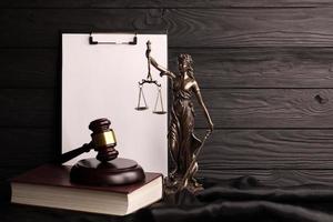 Lady justice or justitia the Roman goddess of Justice. Statue on brown book with judge gavel on blank paper background with copyspace. Concept of judicial trial, courtroom process and lawyers work photo