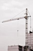 grúas altas de trabajo dentro del lugar con edificios altos en construcción contra un cielo azul claro. Grúa y construcción de progreso de trabajo. tono retro foto