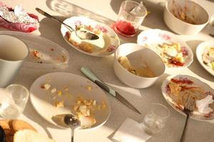 platos sucios vacíos con cucharas y tenedores en la mesa después de la comida. concepto de final de banquete. platos sin lavar foto