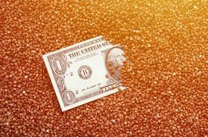 The background texture of a large pile of buckwheat, in the middle of which you see a bill of one US dollar. The concept of higher prices for cereals photo