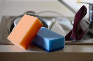 A few sponges lie on the background of the sink with dirty dishes photo