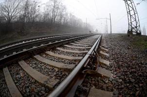 The railway track in a misty morning. A lot of rails and sleepers go into the misty horizon. Fisheye photo with increased distortion