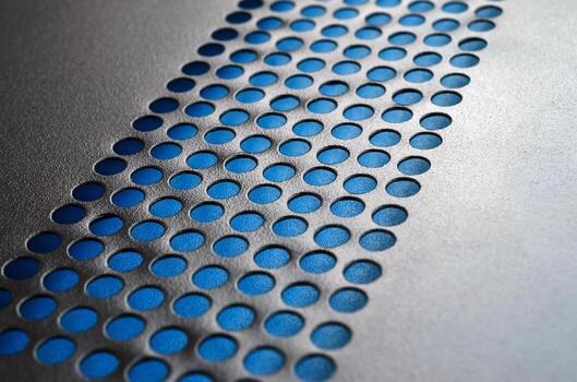 Black metal computer case panel mesh with holes on blue background. Abstract close up image photo