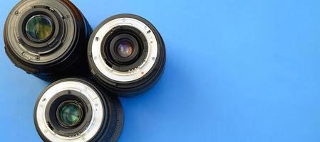 Several photographic lenses lie on a bright blue background. Space for text photo