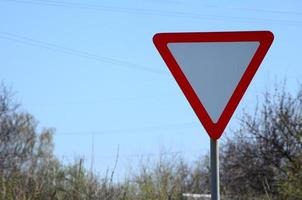 Traffic sign in the form of a white triangle. Give way photo