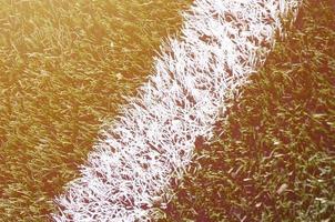 White stripe on a bright green artificial grass soccer field photo