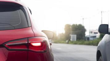 View from behind of red car taillights. With turn on brake light. Sotp on the asphalt road. Beside of road with blurred of green grass and small city under white sky. photo