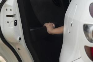 Hand of young hold the car door opener of white car. Car paking at outdoor. photo