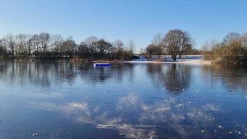 Blick über den zugefrorenen See mit Reflexionen des blauen Himmels bei klarem Wetter. video