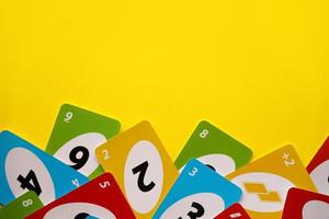 TERNOPIL, UKRAINE - MAY 15, 2022 Many colorful UNO game cards on yellow background. UNO is an American shedding-type card game that is played with a specially printed deck photo