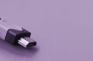 cable de computadora hdmi de audio y video negro sobre fondo púrpura. primer plano del cable de conexión de entretenimiento doméstico para sonido y video foto