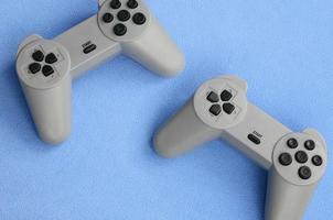 Playing games concept. Two pad joysticks lies on the blanket of furry blue fleece fabric. Controllers for video games on a background texture of light blue soft plush fleece material photo