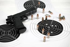 Gun and many bullets shooting targets on white table in shooting range polygon. Training for aiming and shooting photo