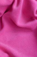 The blanket of furry pink fleece fabric. A background of light pink soft plush fleece material with a lot of relief folds photo