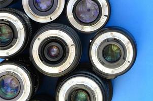 Several photographic lenses lie on a bright blue background. Space for text photo