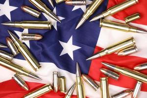 muchas balas y cartuchos amarillos de 9 mm y 5,56 mm en la bandera de los estados unidos. concepto de tráfico de armas en territorio estadounidense u operaciones especiales foto
