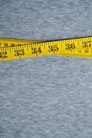 Yellow measuring tape lies on a gray knitted fabric photo