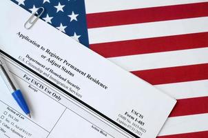 I-485 Application to register permanent residence or adjust status blank form lies on United States flag with blue pen from Department of Homeland Security photo