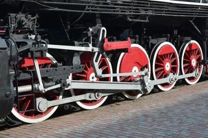 Wheels of the old black steam locomotive of Soviet times. The side of the locomotive with elements of the rotating technology of old trains photo