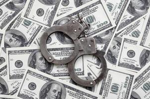 Police handcuffs lie on a lot of dollar bills. The concept of illegal possession of money, illegal transactions with US dollars. Economic Crime photo