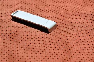 A modern portable USB wi-fi adapter is placed on the red sportswear made of polyester nylon fiber photo